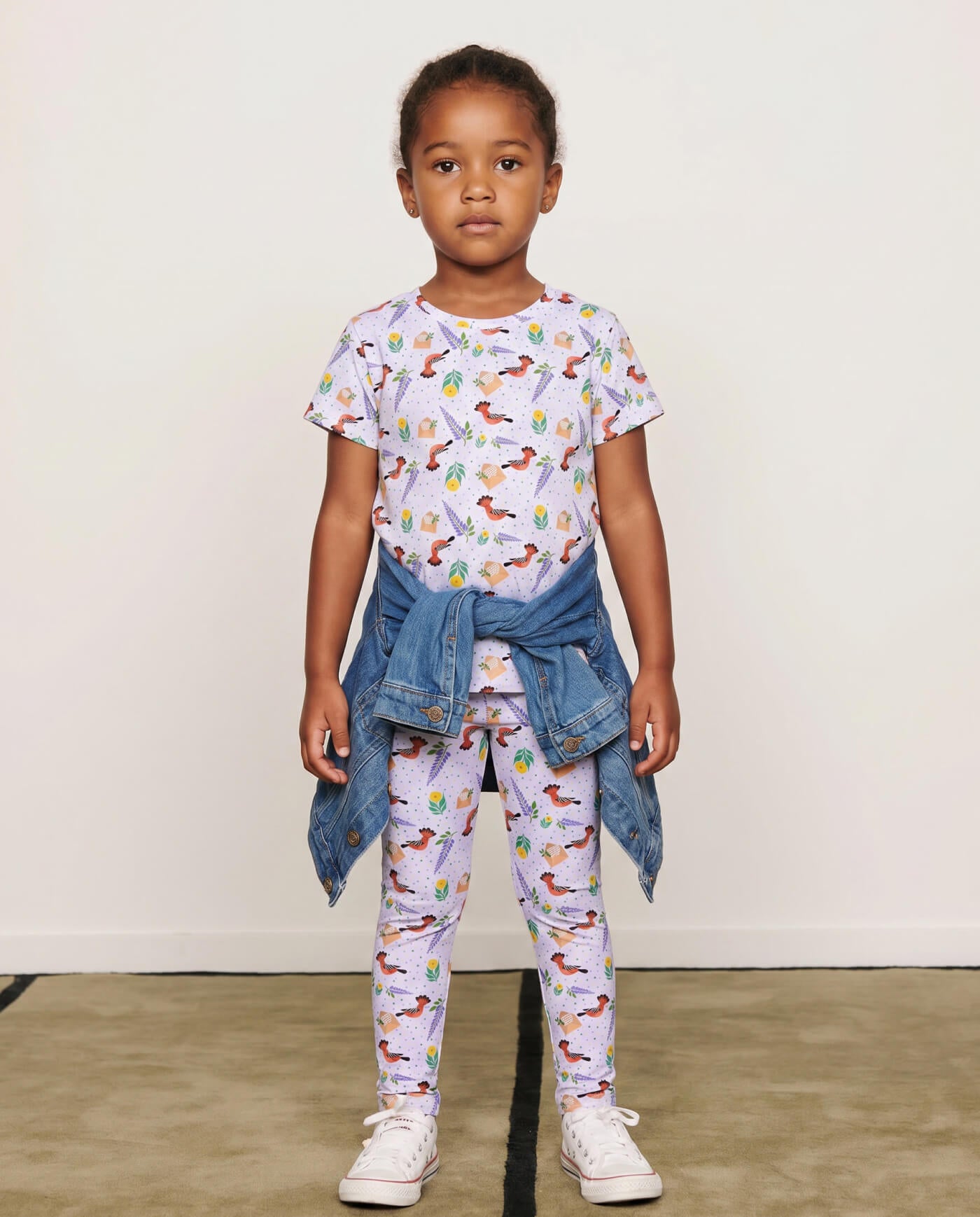 Child wearing hoopoe bird leggings and matching t-shirt with a denim jacket tied at the waist.