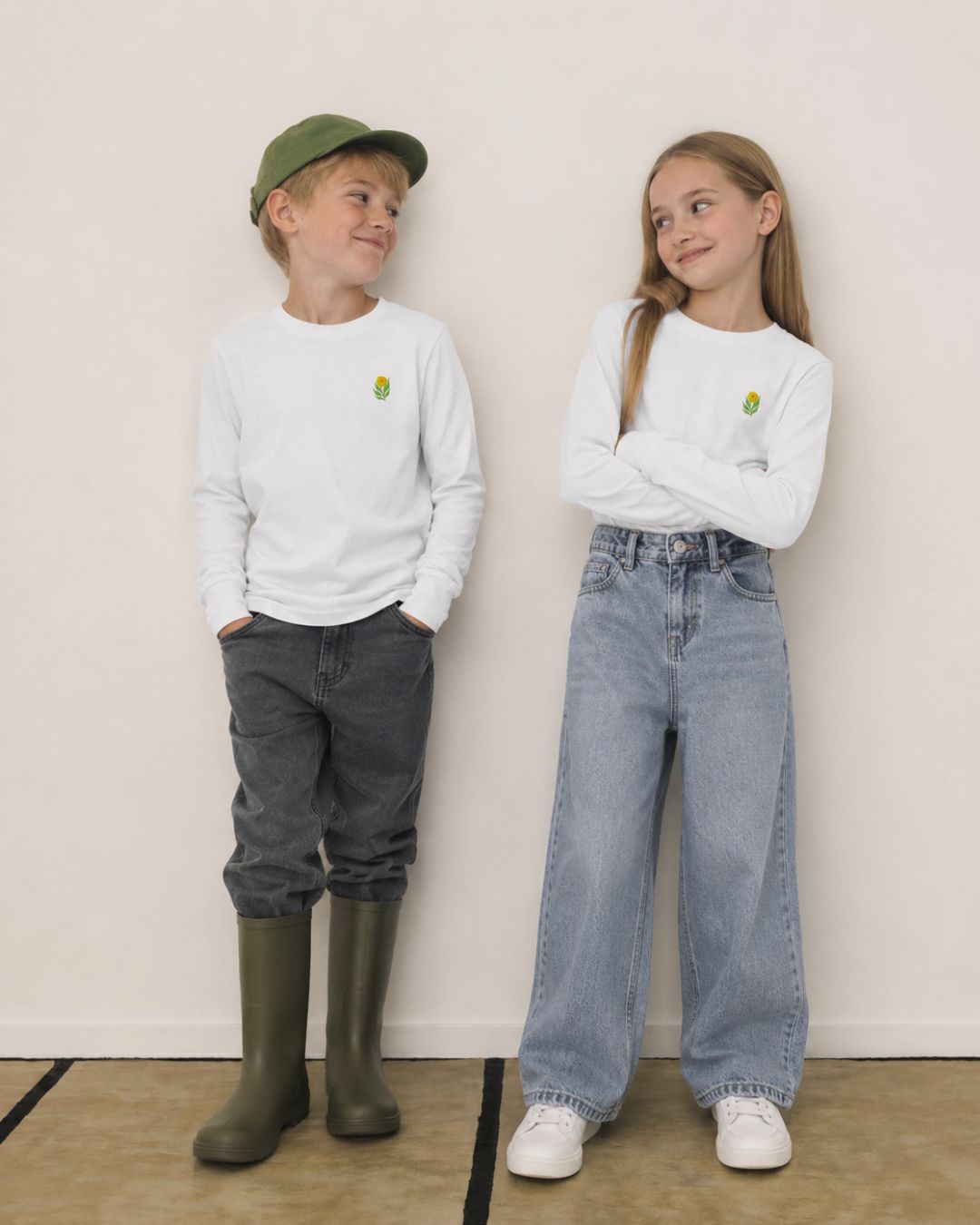 Boy and girl wearing matching white embroidered long sleeve shirts styled with relaxed denim and rain boots in modern kids streetwear look