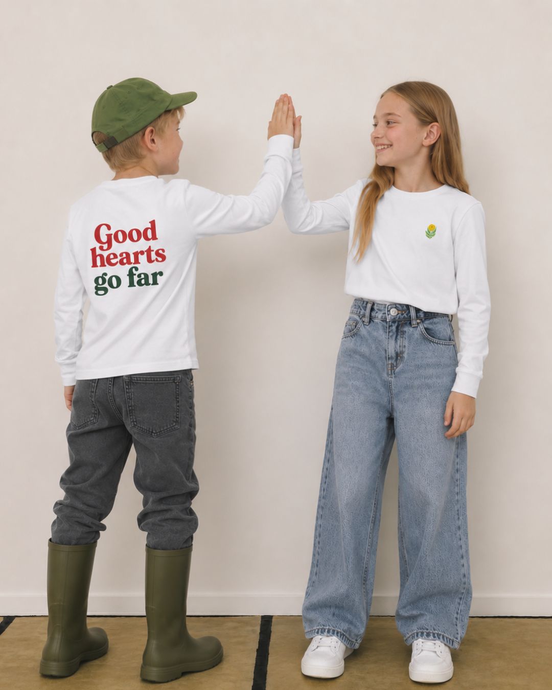Boy and girl wearing matching white graphic long sleeve shirts giving each other a high five