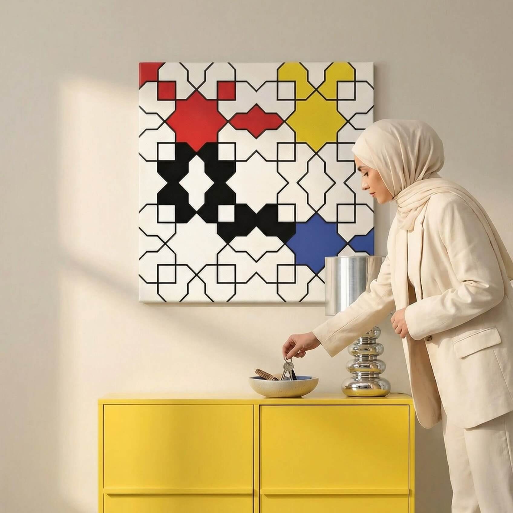 Woman in a beige outfit standing next to a yellow cabinet with a colorful geometric mondrian-isnpired patterned wall art.