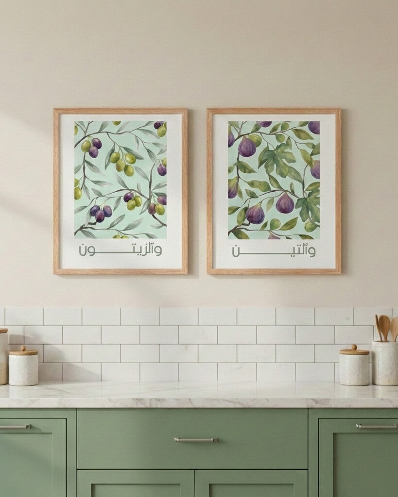 Two framed botanical prints featuring olive branches and fig leaves with Arabic text “wa-z-zaytūn” and “wa-t-tīn”, styled above a green kitchen counter with white tiles